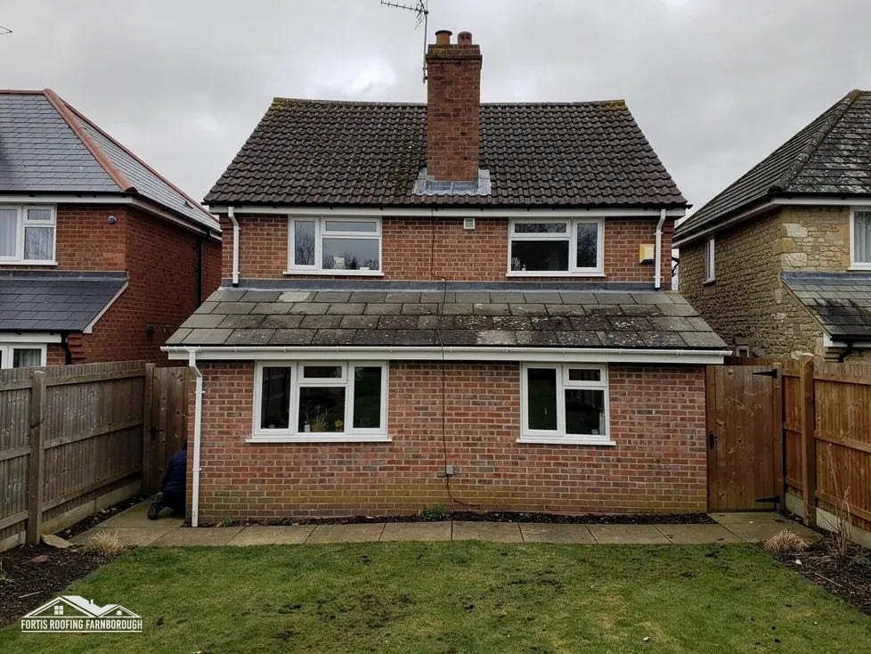 Back of a 1960s brick house with a concrete tile roof
