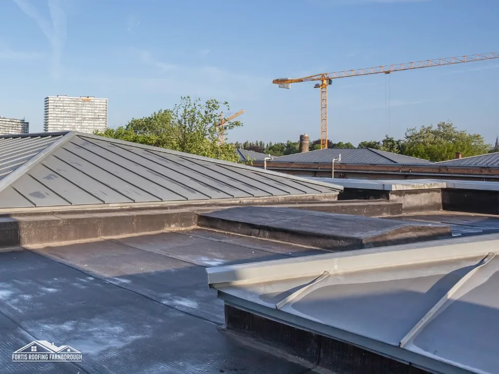 Grey single-ply flat roof with roof lanterns and a crane beyond