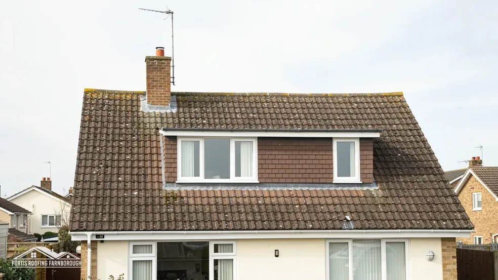 Detached house with a brown tile roof and a wide box dormer