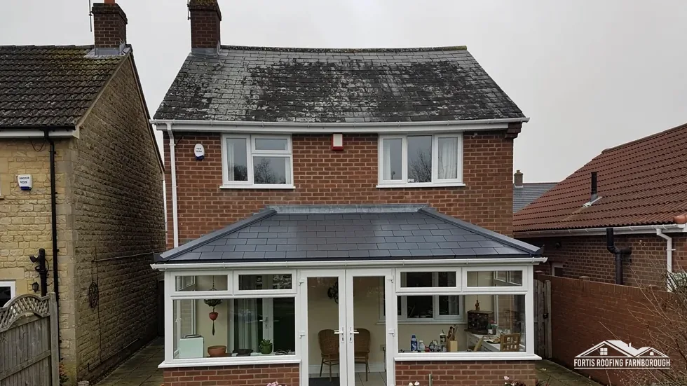 Back of a brick house with a conservatory under a tiled roof